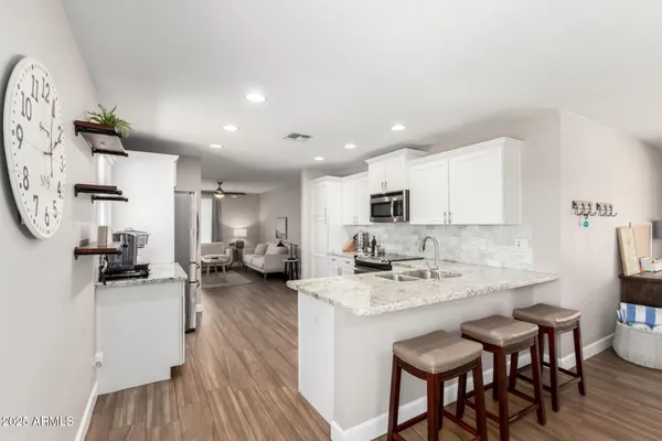 a living room with stainless steel appliances furniture a rug and a kitchen view