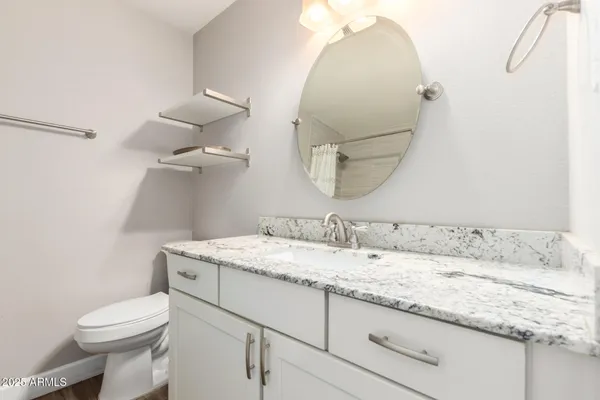 a bathroom with a granite countertop sink a toilet and a mirror
