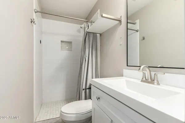 a bathroom with a sink a toilet a mirror and shower