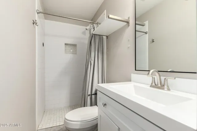 a bathroom with a sink a toilet a mirror and shower