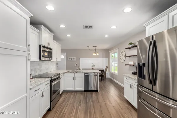 a kitchen with stainless steel appliances granite countertop a refrigerator a stove top oven a sink and dishwasher