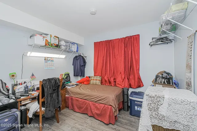 a bedroom with a bed and dresser with the shoe rack