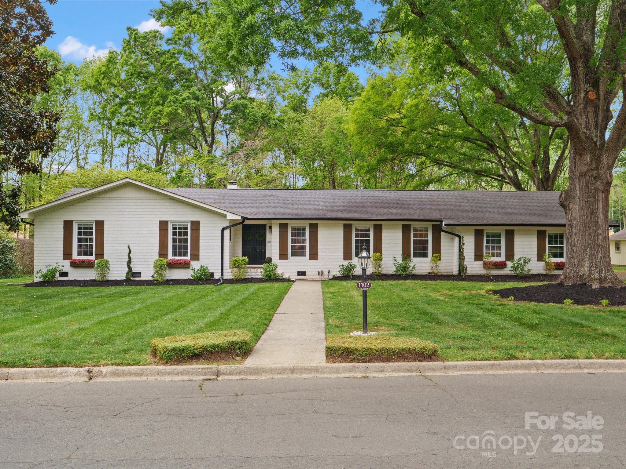 a front view of a house with a garden and trees