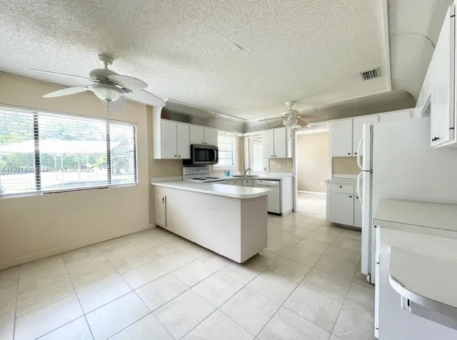 a kitchen with a refrigerator a stove top oven and white cabinets