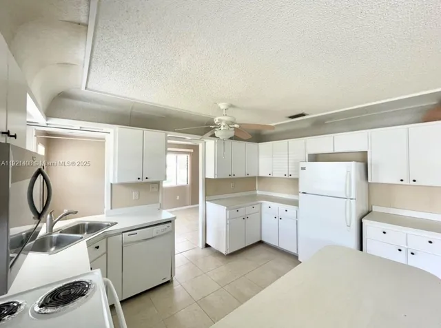 a kitchen with white cabinets a sink and appliances