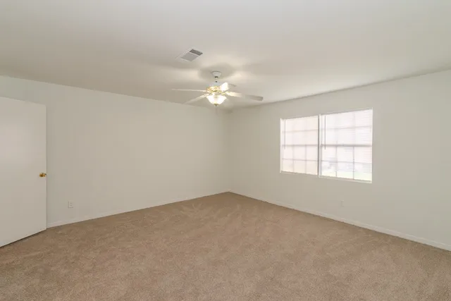 an empty room with a window and a chandelier fan