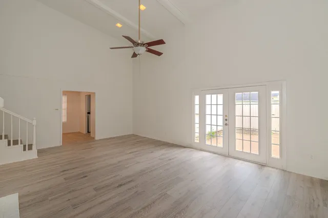 an empty room with wooden floor cabinet and windows