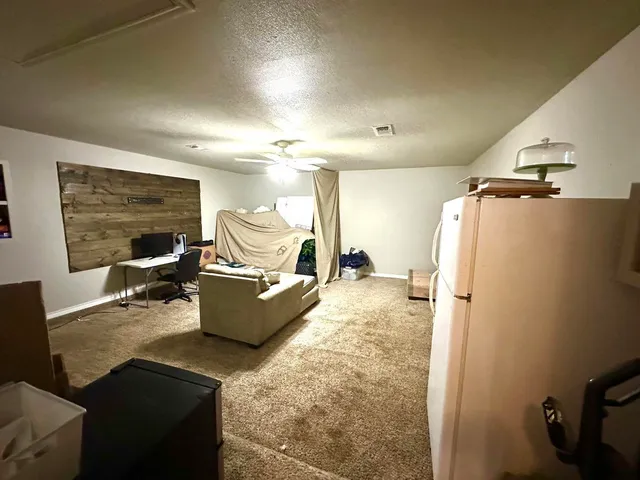 a living room with furniture and a refrigerator