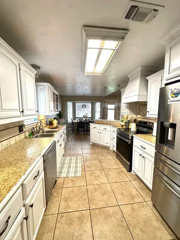 a kitchen with stainless steel appliances granite countertop a stove top oven a sink a counter space and cabinets