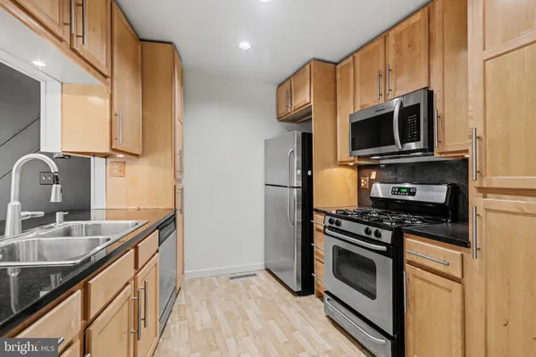 a kitchen with stainless steel appliances a stove microwave and sink