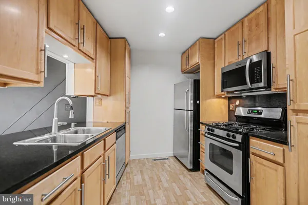 a kitchen with stainless steel appliances a stove a sink a microwave and refrigerator