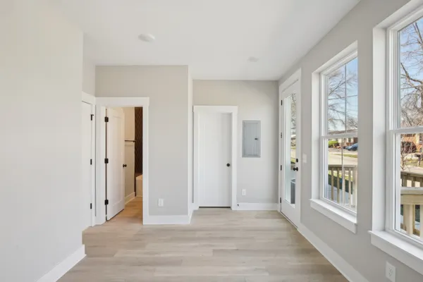 a view of an empty room with wooden floor and a window
