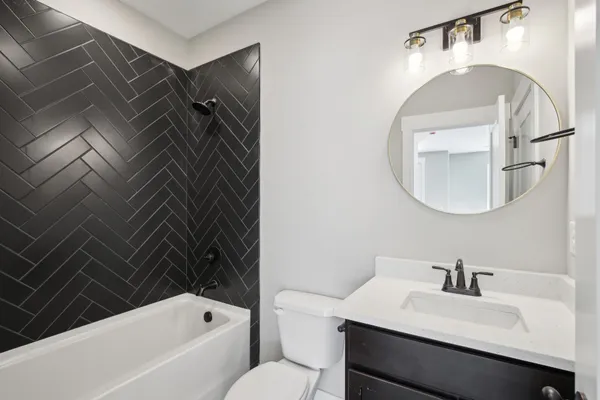 a bathroom with a sink vanity mirror and bathtub