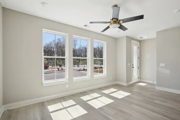 a view of empty room with wooden floor and fan