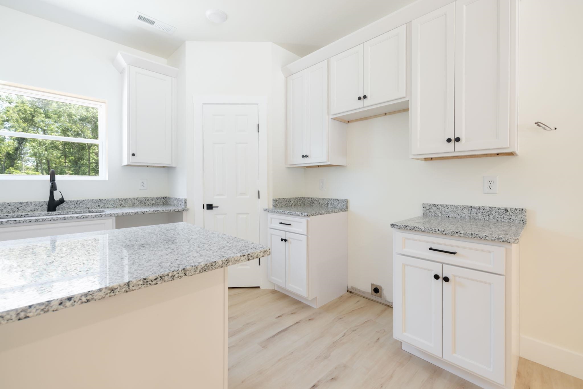 37 William Teague Lane Ramer, TN 38367 - Photo 20 of 39 Kitchen featuring a central island, white cabinetry with black hardware, light-toned wood-finish flooring, and speckled countertops