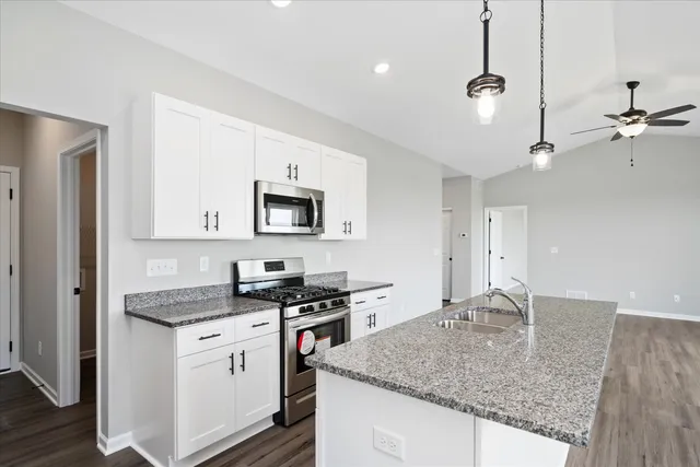 a kitchen with granite countertop a sink cabinets and stainless steel appliances