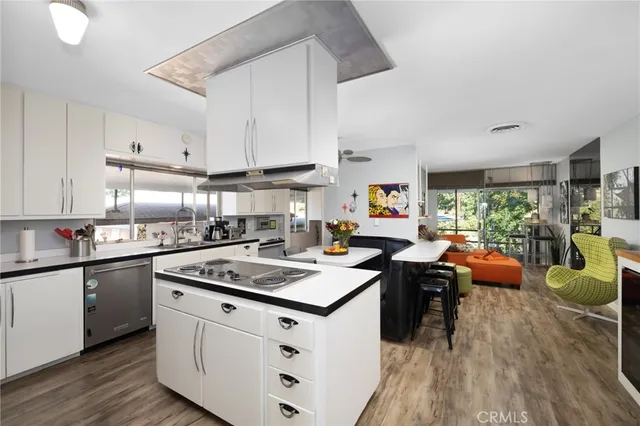 a kitchen with a stove a sink dishwasher and a refrigerator with wooden floor