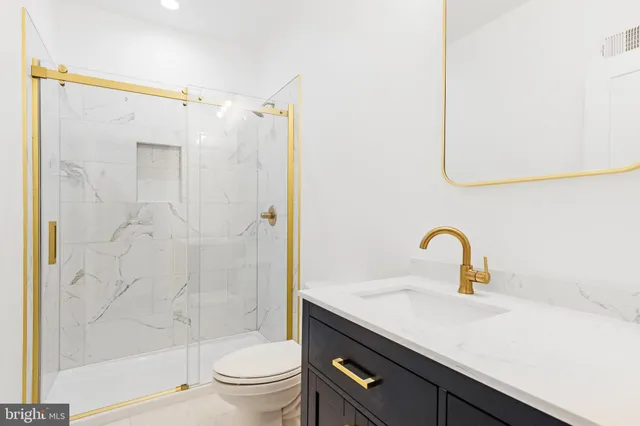 a bathroom with a shower sink vanity and toilet