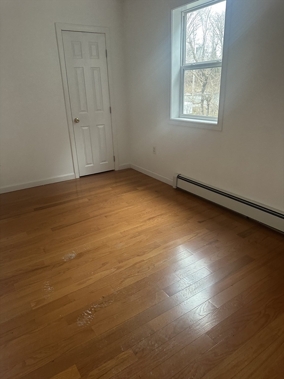 115-117 Stone Street, Unit 1 Clinton, MA 01510 - Photo 5 of 8 an empty room with wooden floor and windows