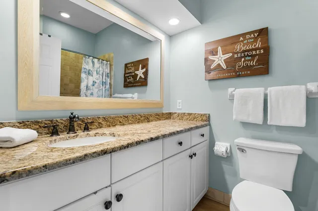 a bathroom with a granite countertop sink mirror and toilet