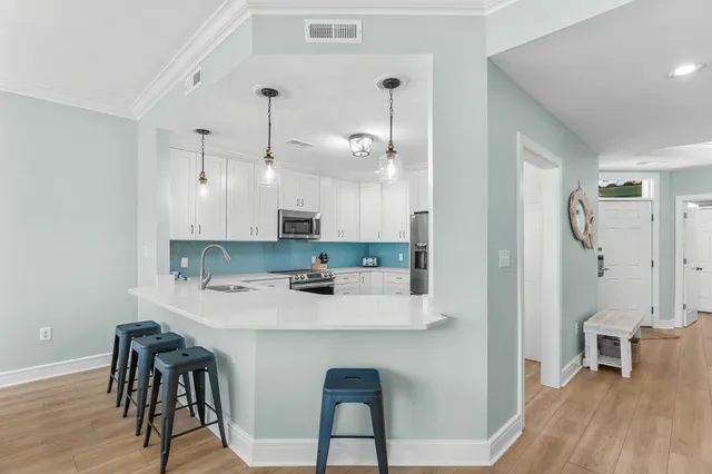 a kitchen with stainless steel appliances kitchen island a table chairs in it and wooden floors
