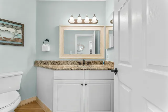 a bathroom with a granite countertop toilet sink and mirror