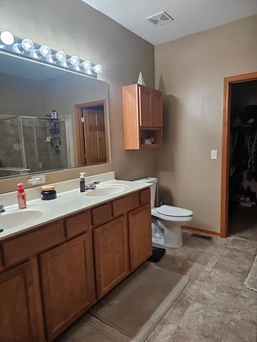 a bathroom with a toilet sink double vanity and mirror