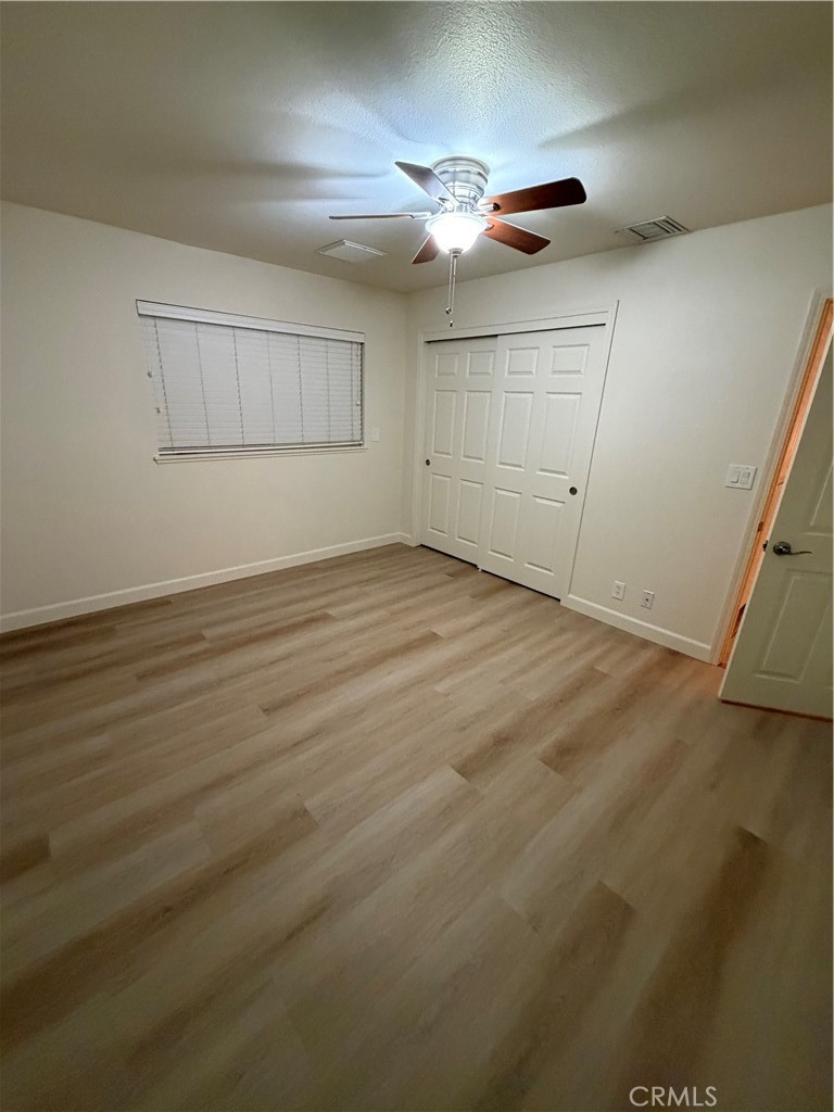 209 Kimberly Lane Ridgecrest, CA 93555 - Photo 56 of 62 an empty room with wooden floor fan and windows