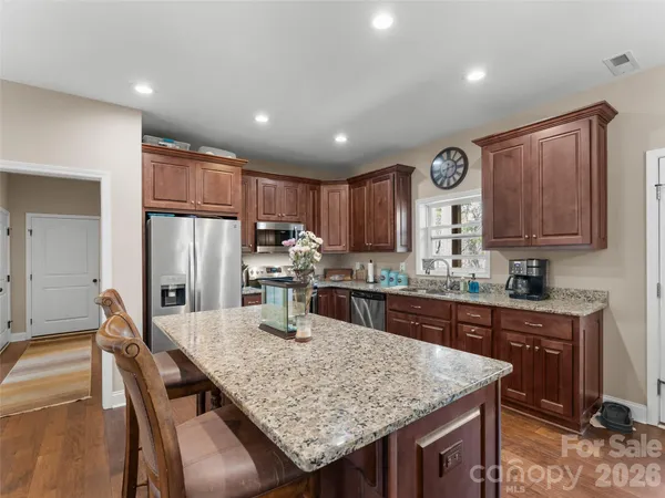 a kitchen with stainless steel appliances granite countertop a sink a stove a microwave and wooden cabinets