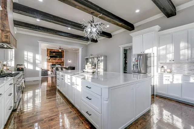 a large white kitchen with lots of counter space and chandelier
