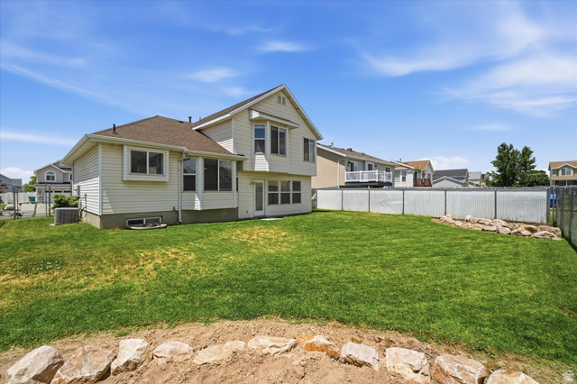 5576 South 4100th Street West Roy, UT 84067 - Photo 34 of 35 Expansive backyard featuring a manicured lawn, white privacy fencing, and a decorative rock border
