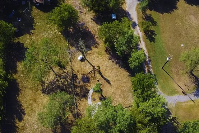 an aerial view of residential houses with outdoor space and trees all around