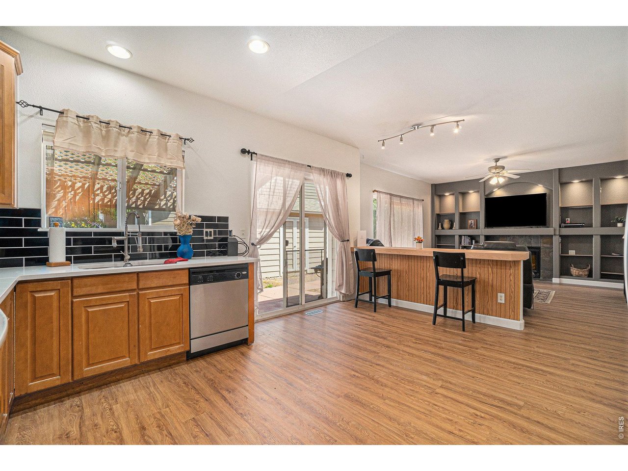 11226 Dover Street Firestone, CO 80504 - Photo 6 of 27 a open kitchen with stainless steel appliances kitchen island granite countertop a stove top oven a sink dishwasher and white cabinets with wooden floor