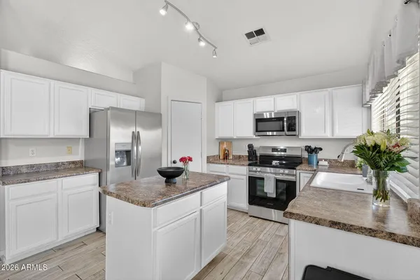 a kitchen with granite countertop stainless steel appliances a sink dishwasher a refrigerator a stove top oven a granite counter space and cabinets
