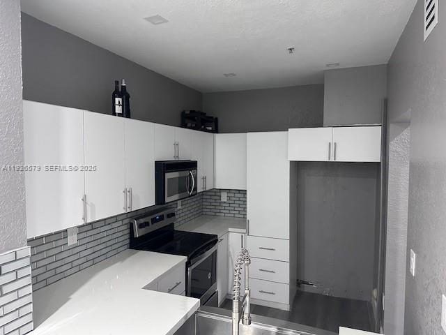 7100 Northwest 177th Street, Unit 100 Hialeah, FL 33015 - Photo 2 of 13 a kitchen with stainless steel appliances a refrigerator and a stove top oven