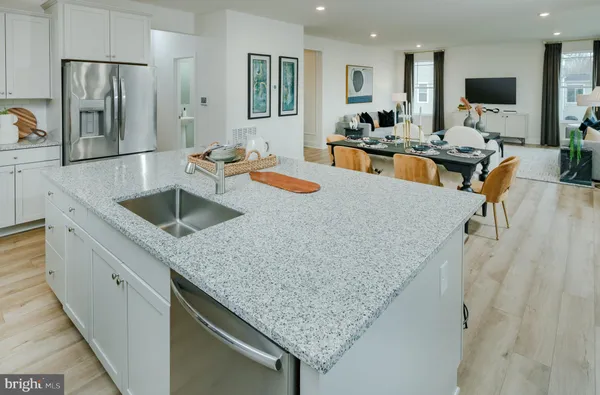 a kitchen with stainless steel appliances granite countertop a table chairs sink and cabinets