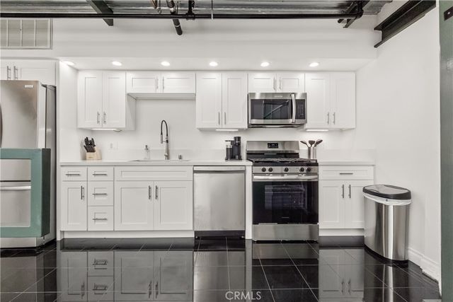 a kitchen with white cabinets and sink