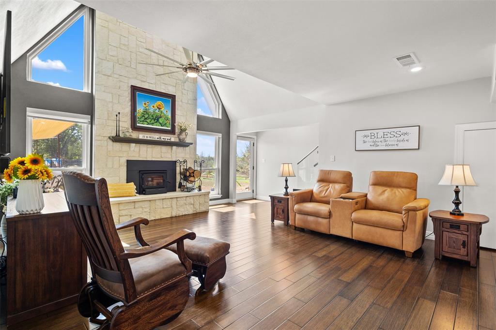 668 Cleve Cole Road Denison, TX 75021 - Photo 4 of 38 Vaulted ceiling with an exposed beam, stone-clad fireplace, wood-finish flooring, and large windows with architectural detailing
