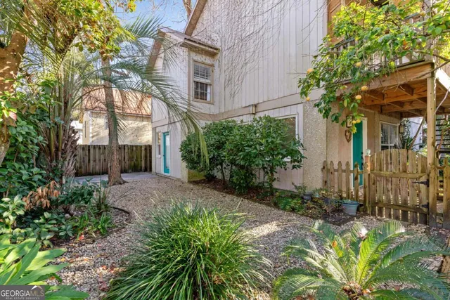 a view of a house with brick walls plants and large tree