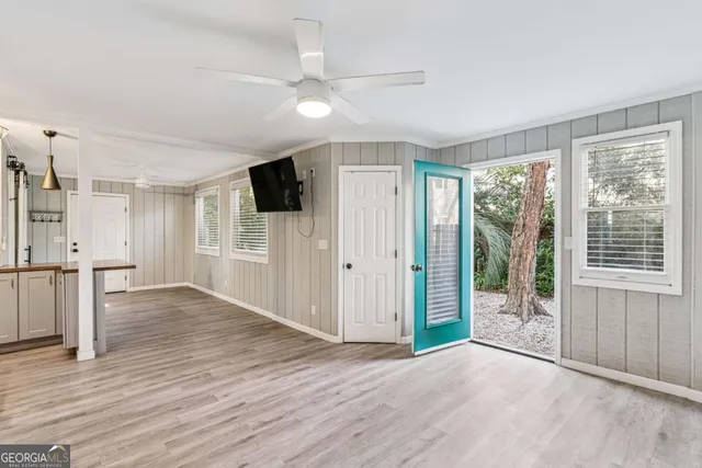 a view of empty room with wooden floor and fan