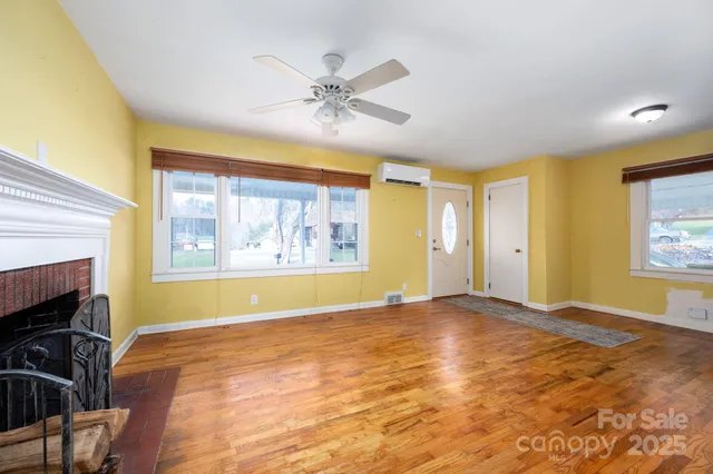 a view of an empty room with window and wooden floor