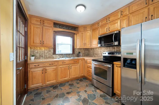 a kitchen with stainless steel appliances granite countertop a refrigerator a sink a stove top oven and a dishwasher