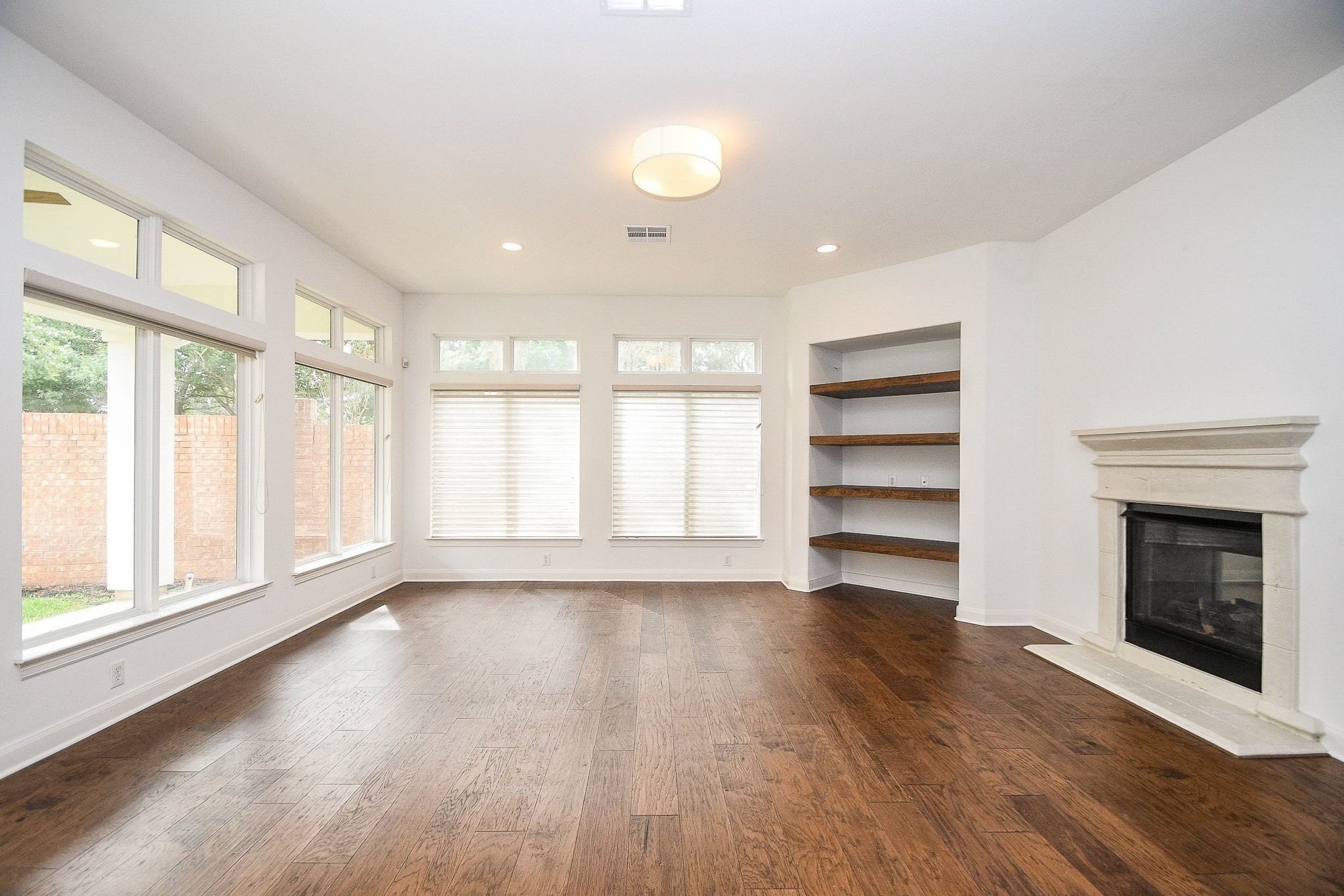2826 Tudor Manor Houston, TX 77082 - Photo 7 of 37 Spacious family room featuring a cozy gas fireplace, custom decorative shelving, abundant natural light, and the added privacy of no back neighbors.