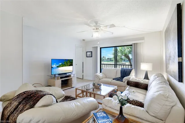 a living room with furniture a flat screen tv and a large window