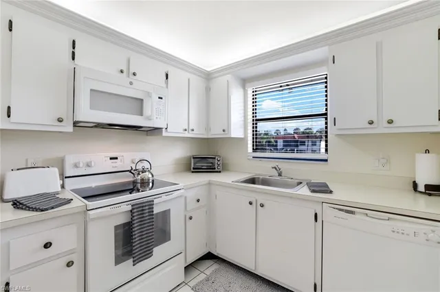 a kitchen with cabinets appliances a sink and a window