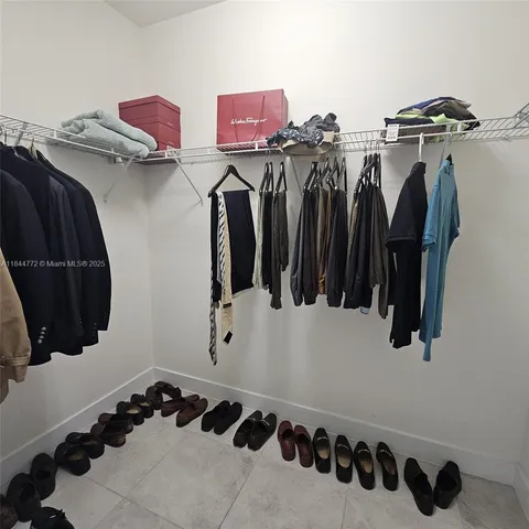a view of walk in closet with clothes and shoes
