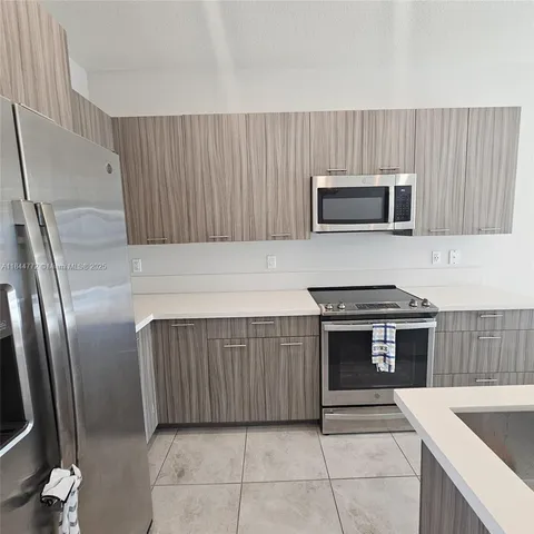 a kitchen with granite countertop a refrigerator and a stove top oven