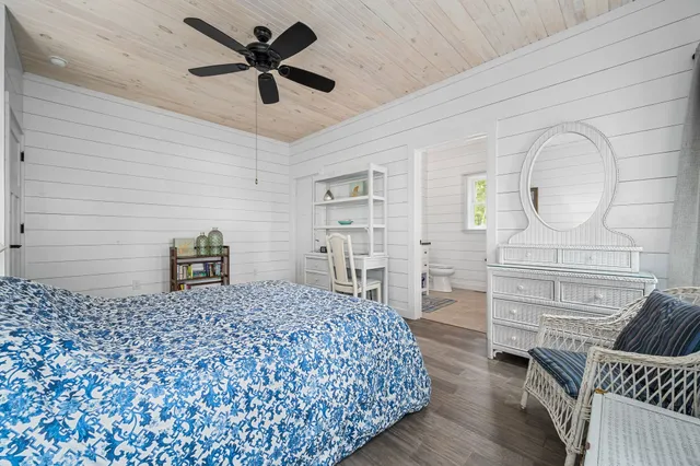a bedroom with a bed a dresser and potted plant