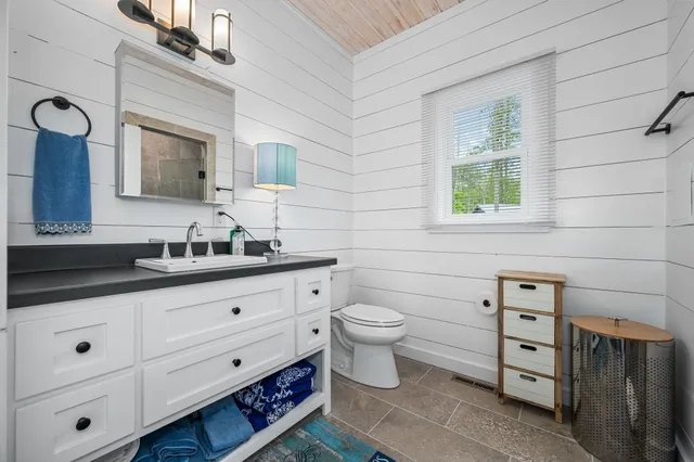 a bathroom with a toilet a sink a mirror and a window