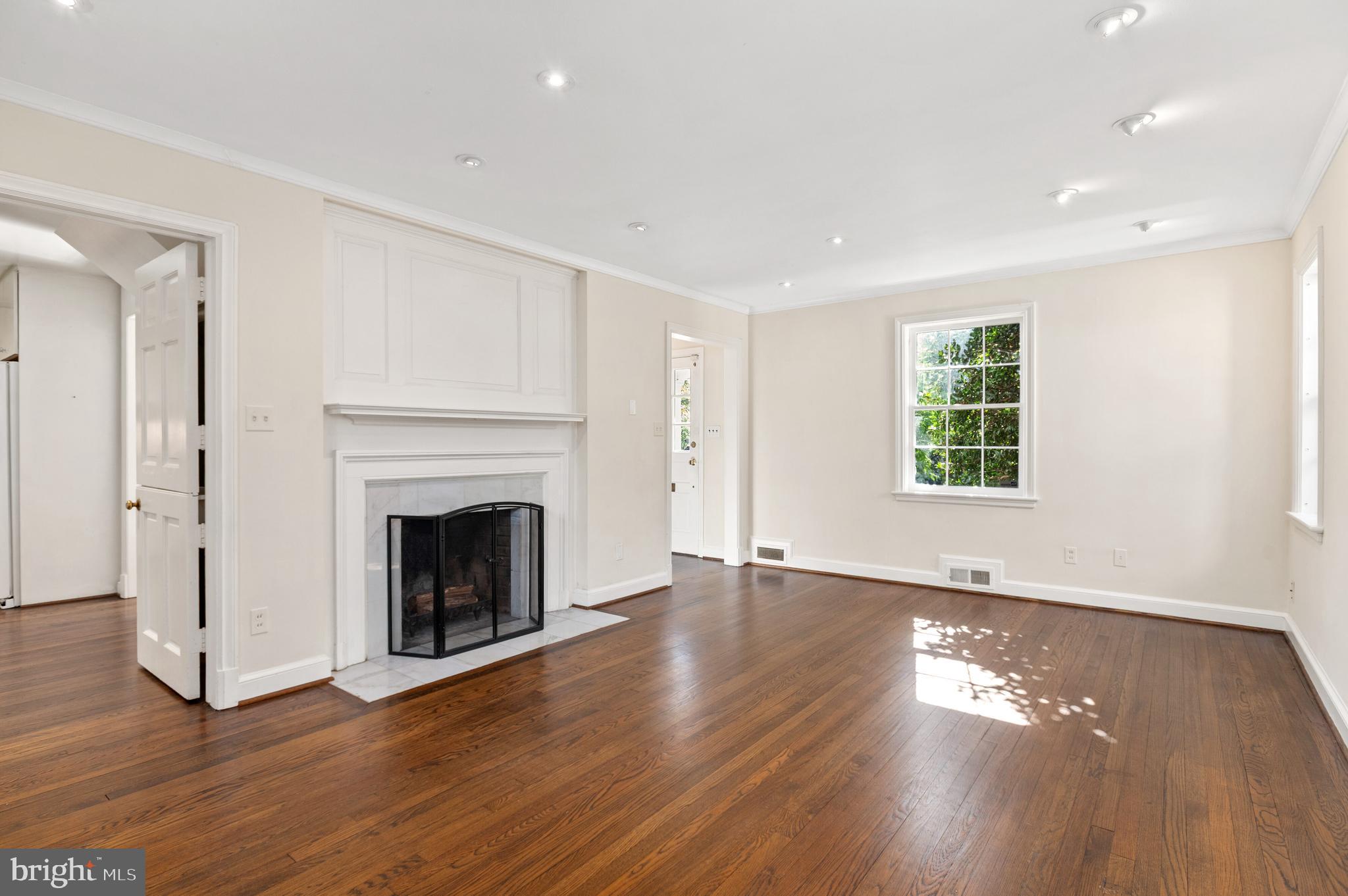 4849 Rodman Street Northwest Washington, DC 20016 - Photo 8 of 30 a view of an empty room with wooden floor fireplace and a window